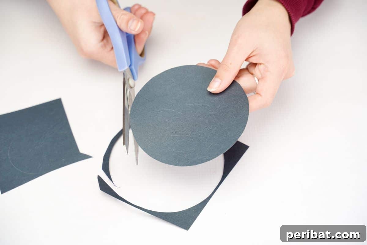 DIY Rustic Wood Slice Snowman Decor 5 Blue scissors carefully cutting a black circle from paper, part of the process for crafting the snowman's hat