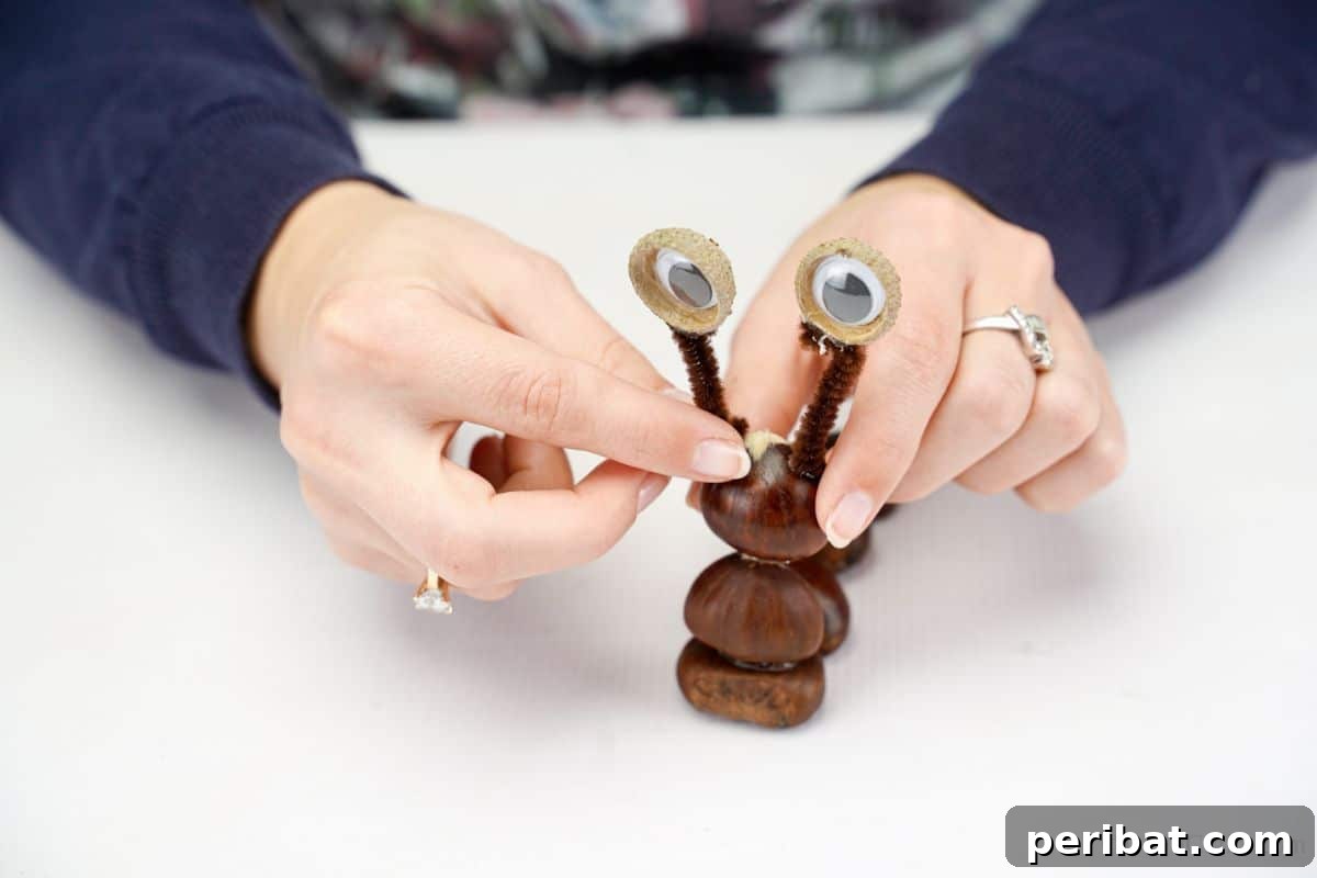 Hand carefully gluing a pipe cleaner antenna onto the top nut of the snail's body, adding the eyes.