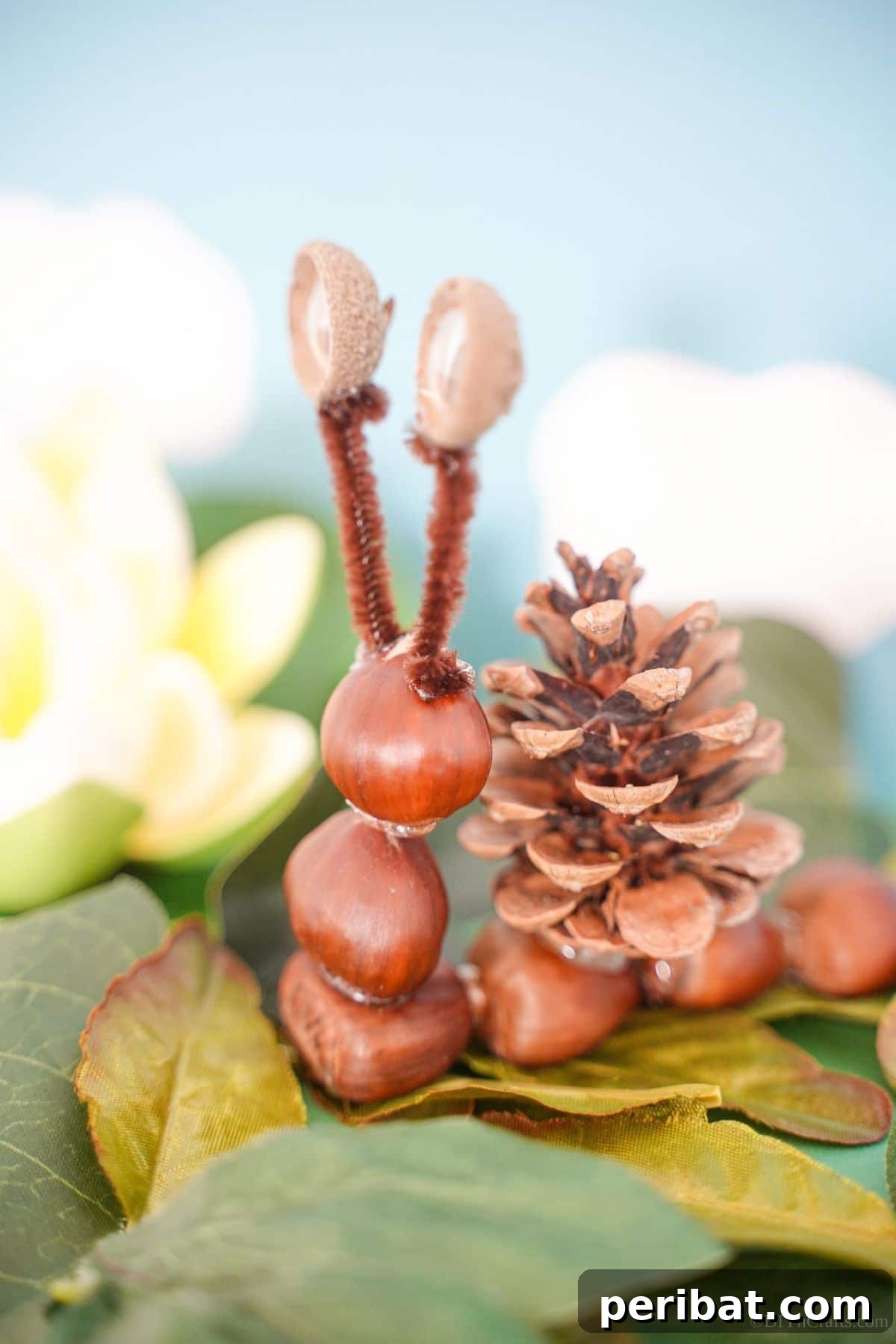 A finished chestnut and pinecone snail resting on fake leaves, highlighting the final product.