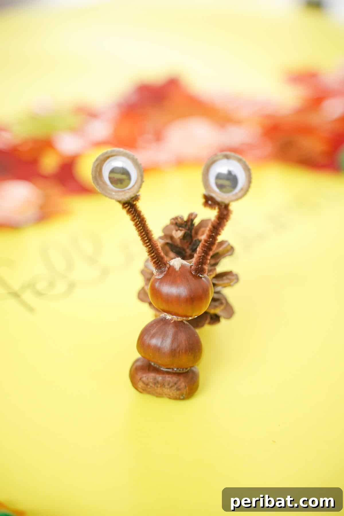 Pinecone and nut snail craft displayed on yellow paper with natural elements, ready for assembly.