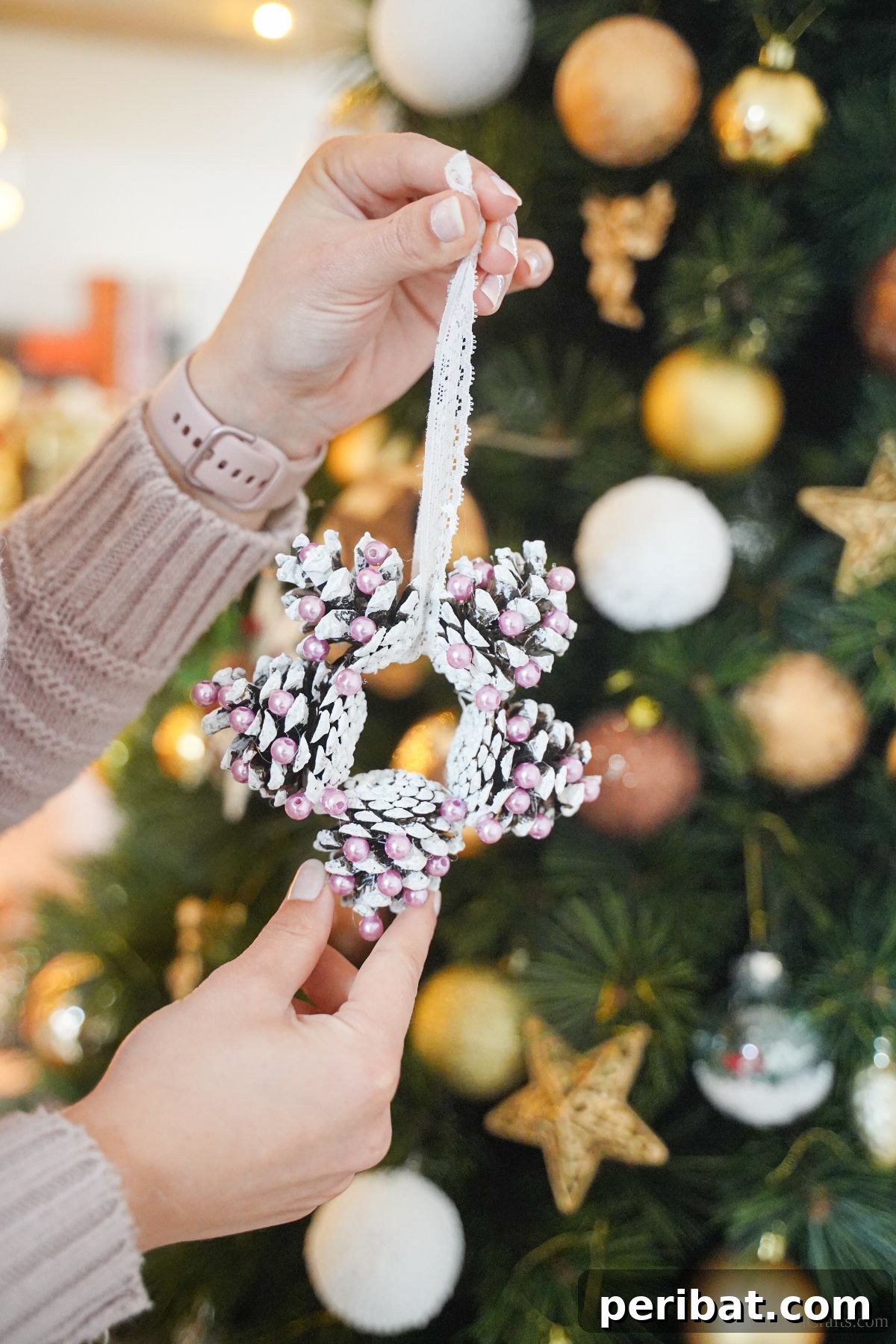 Glistening Bead-Adorned Pinecone Star 13 hand in cream sweater holding white and pink star pinecone ornament