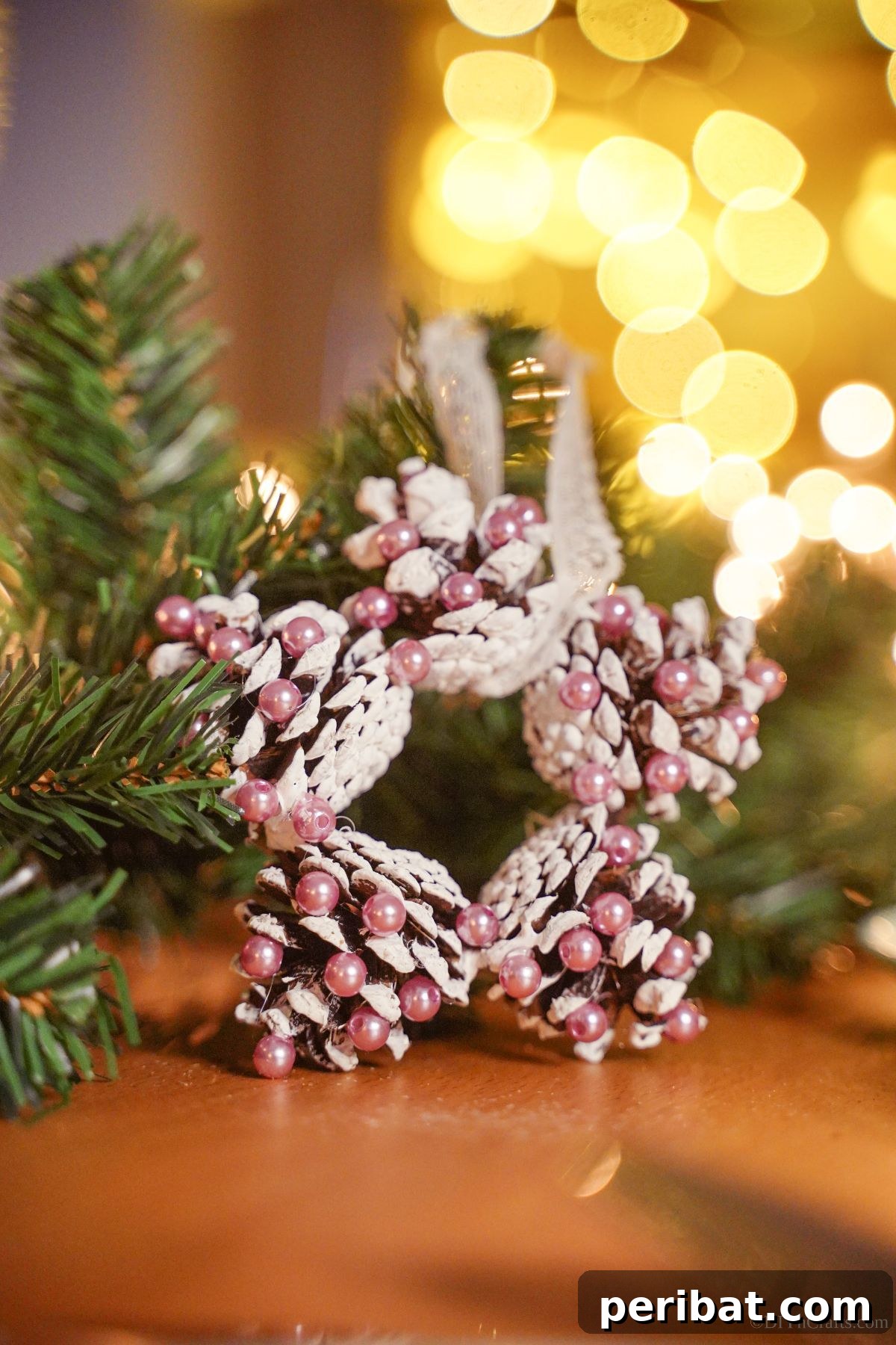 Glistening Bead-Adorned Pinecone Star 16 pinecone star against greenery on table with lights in background