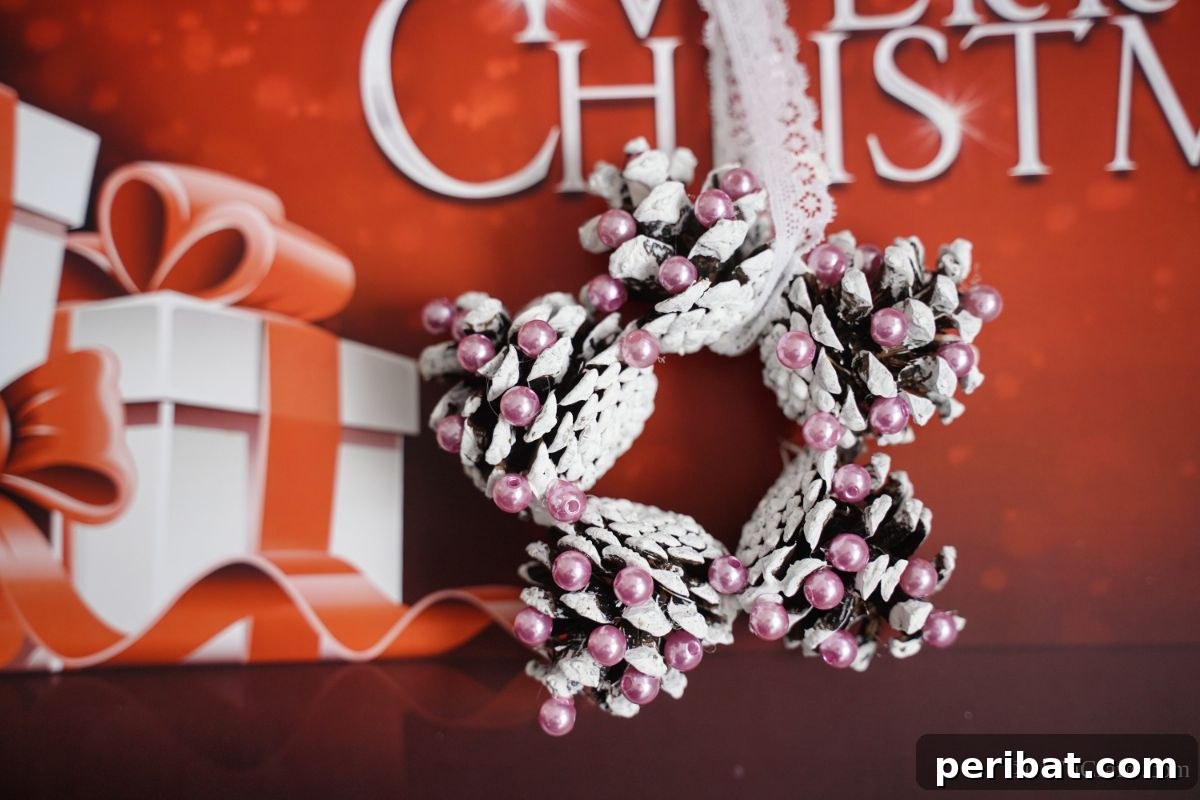 Glistening Bead-Adorned Pinecone Star 6 pink and white star ornament made of pinecones against red paper that says merry christmas