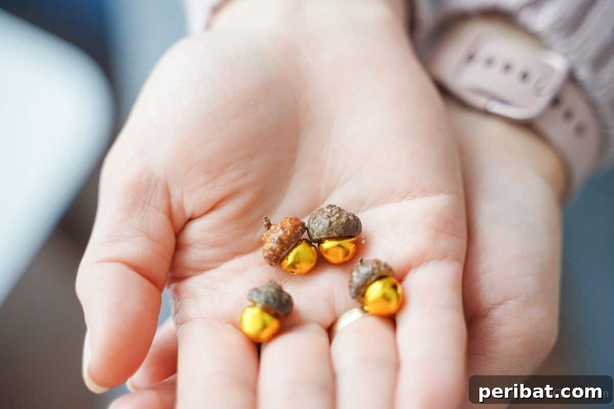 A hand gently displays a collection of mini golden bells, each adorned with a natural acorn cap top