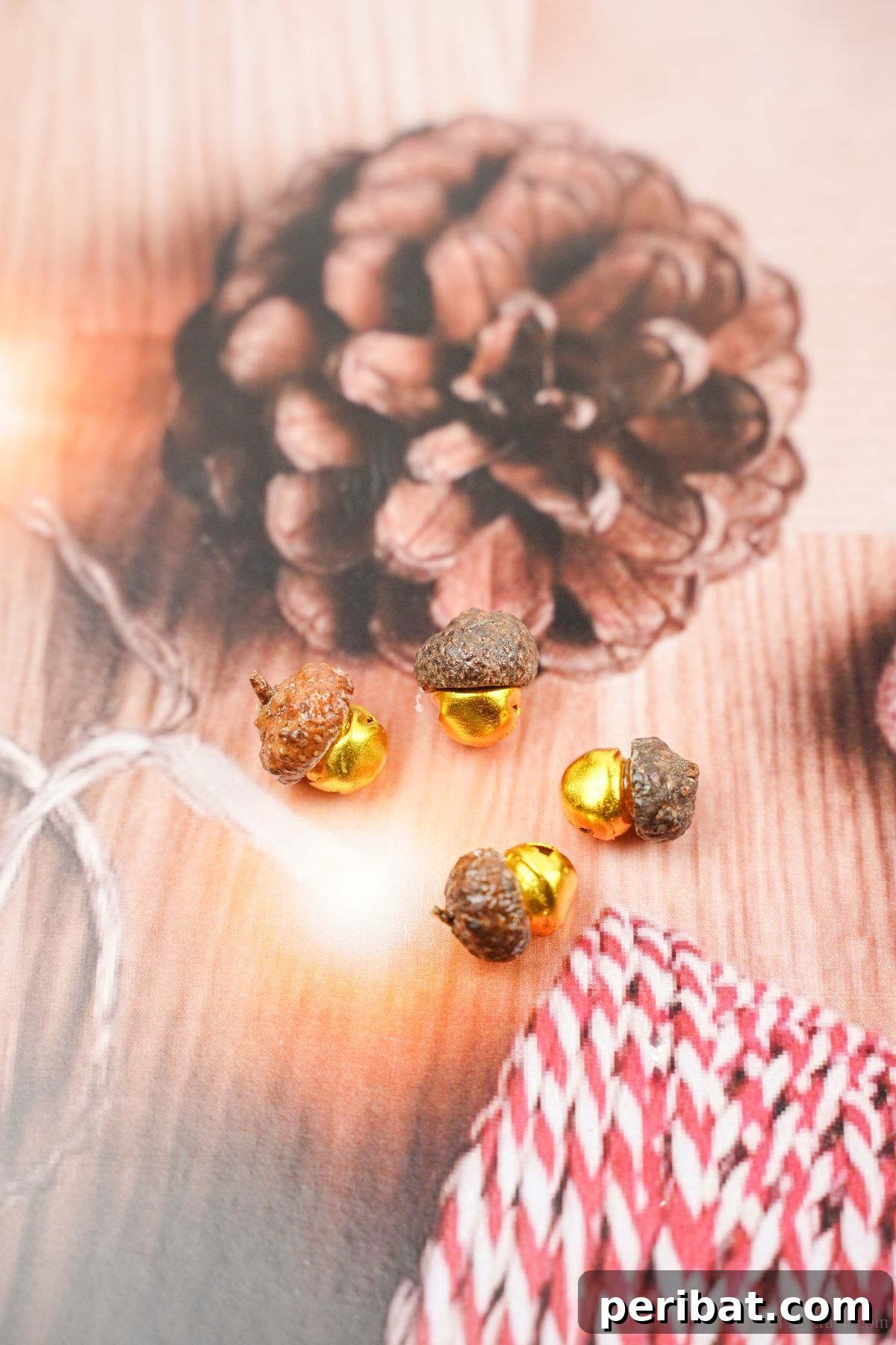 Acorn cap jingle bells resting on holiday paper decorated with pinecones and candy canes