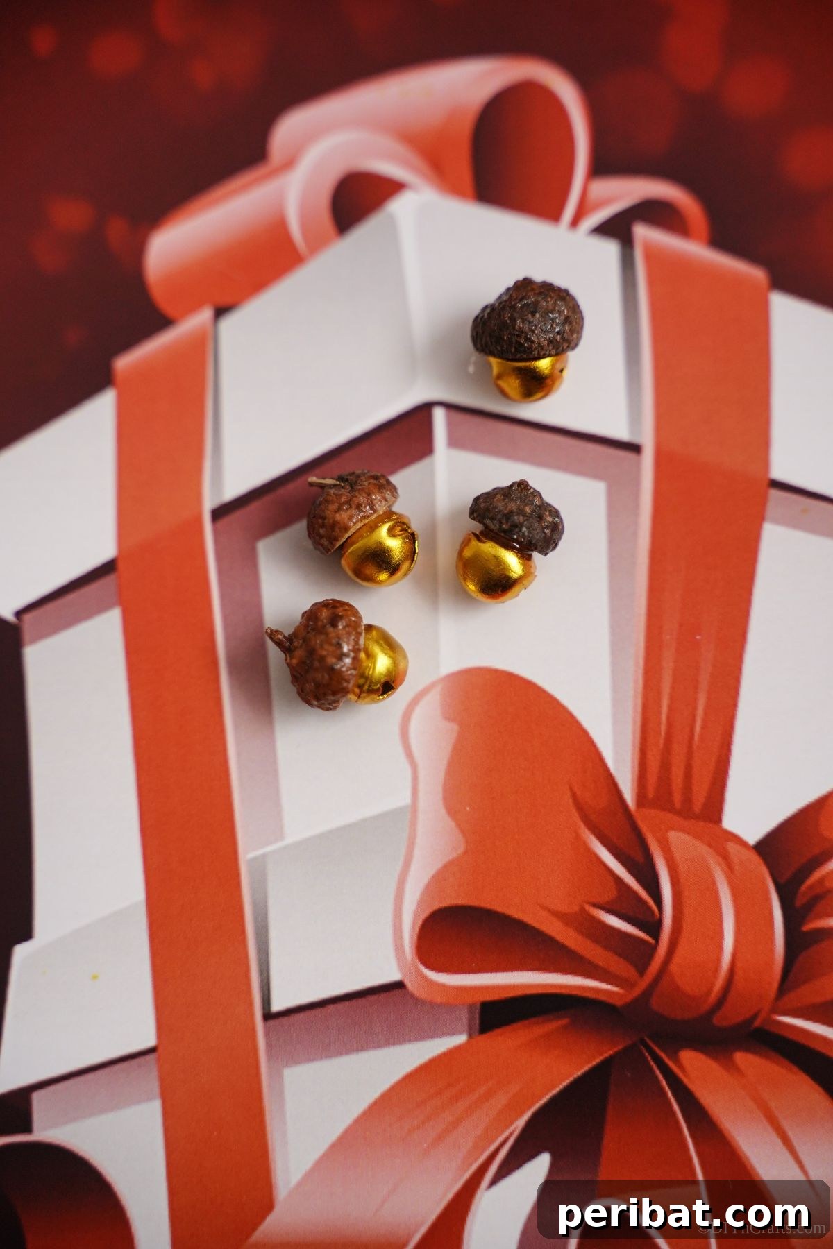 Several beautifully crafted acorn cap bells arranged on festive holiday paper, with a distinct white box design
