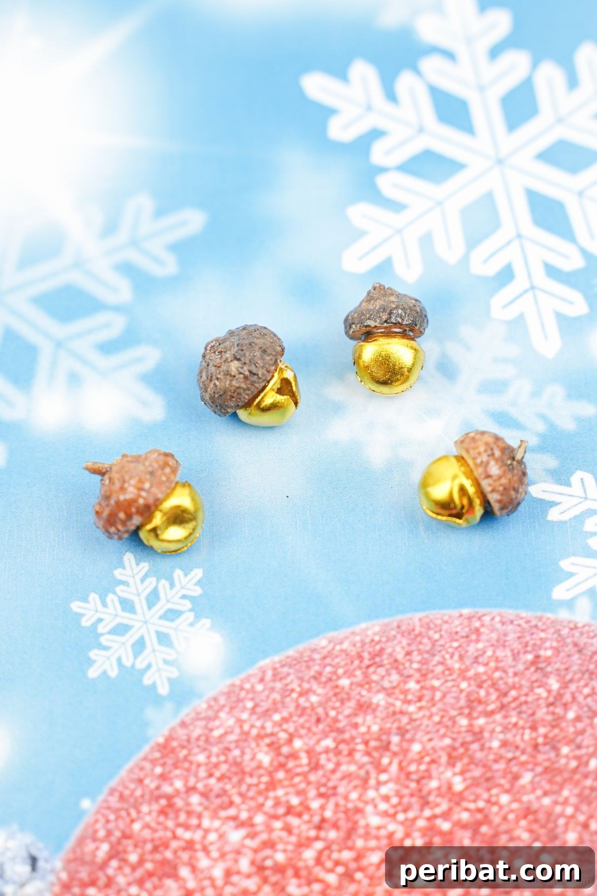 Golden acorn cap jingle bells set against a blue paper background, adorned with white fake snowflakes