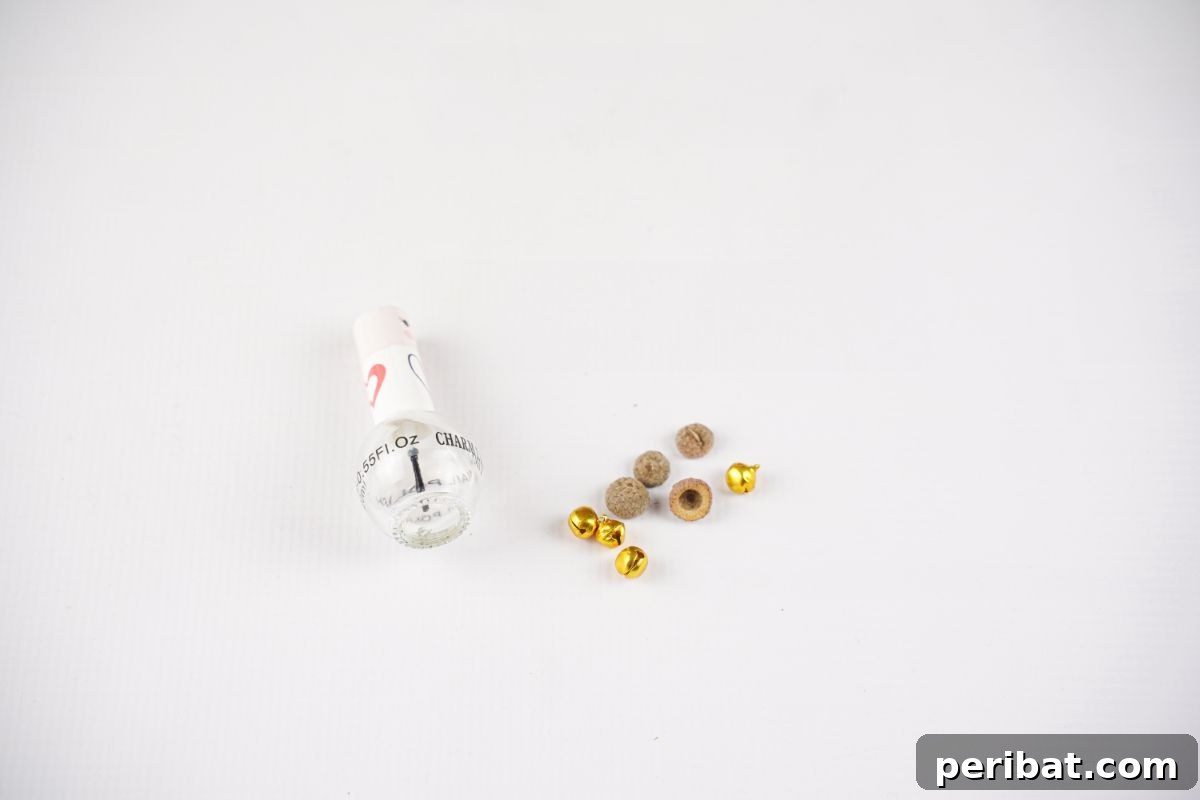 A perfectly arranged display of acorn caps, small bells, and clear nail polish on a clean white table, ready for crafting