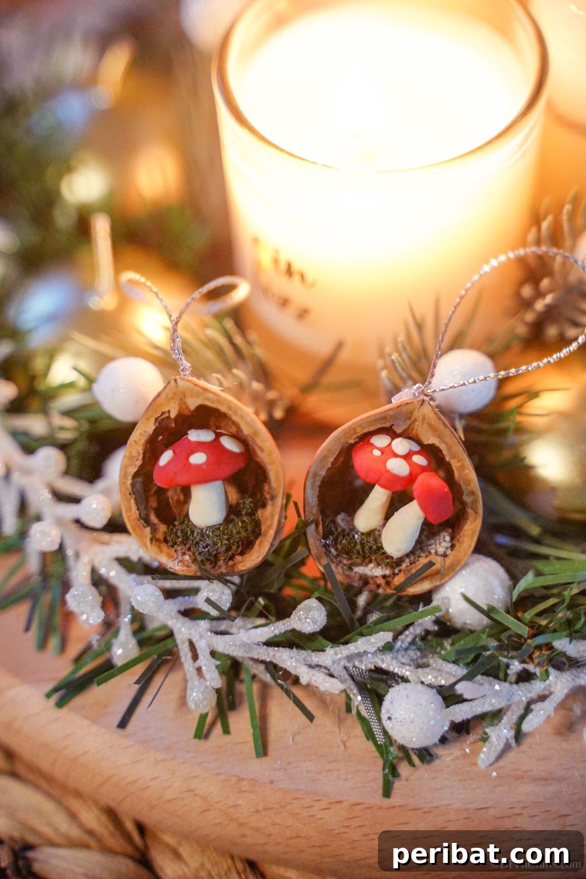 Two walnut shell ornaments featuring miniature mushrooms inside, artfully arranged on holiday greenery beside a softly glowing candle, creating a cozy and natural festive atmosphere.