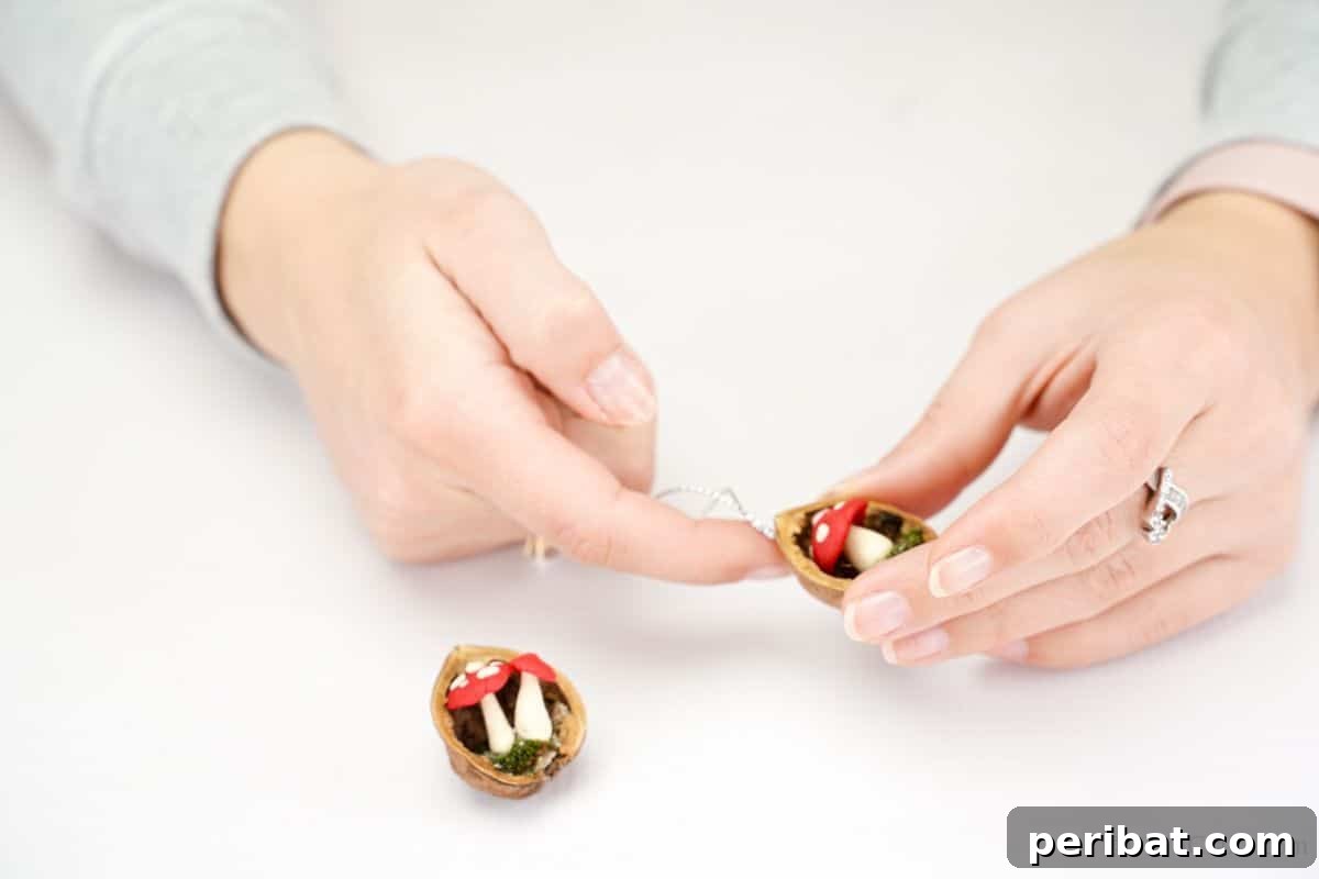 finger holding string to top of ornament