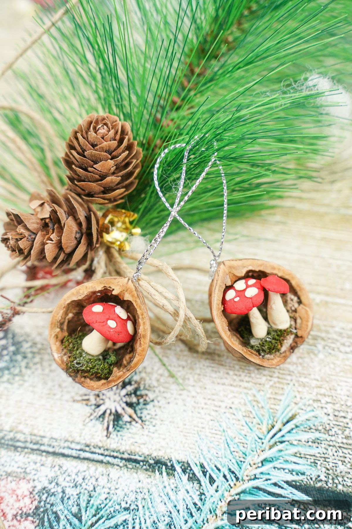 Pinecones and green foliage are arranged on holiday-themed paper, alongside two beautifully crafted walnut shell ornaments, creating a harmonious display of natural Christmas decor.