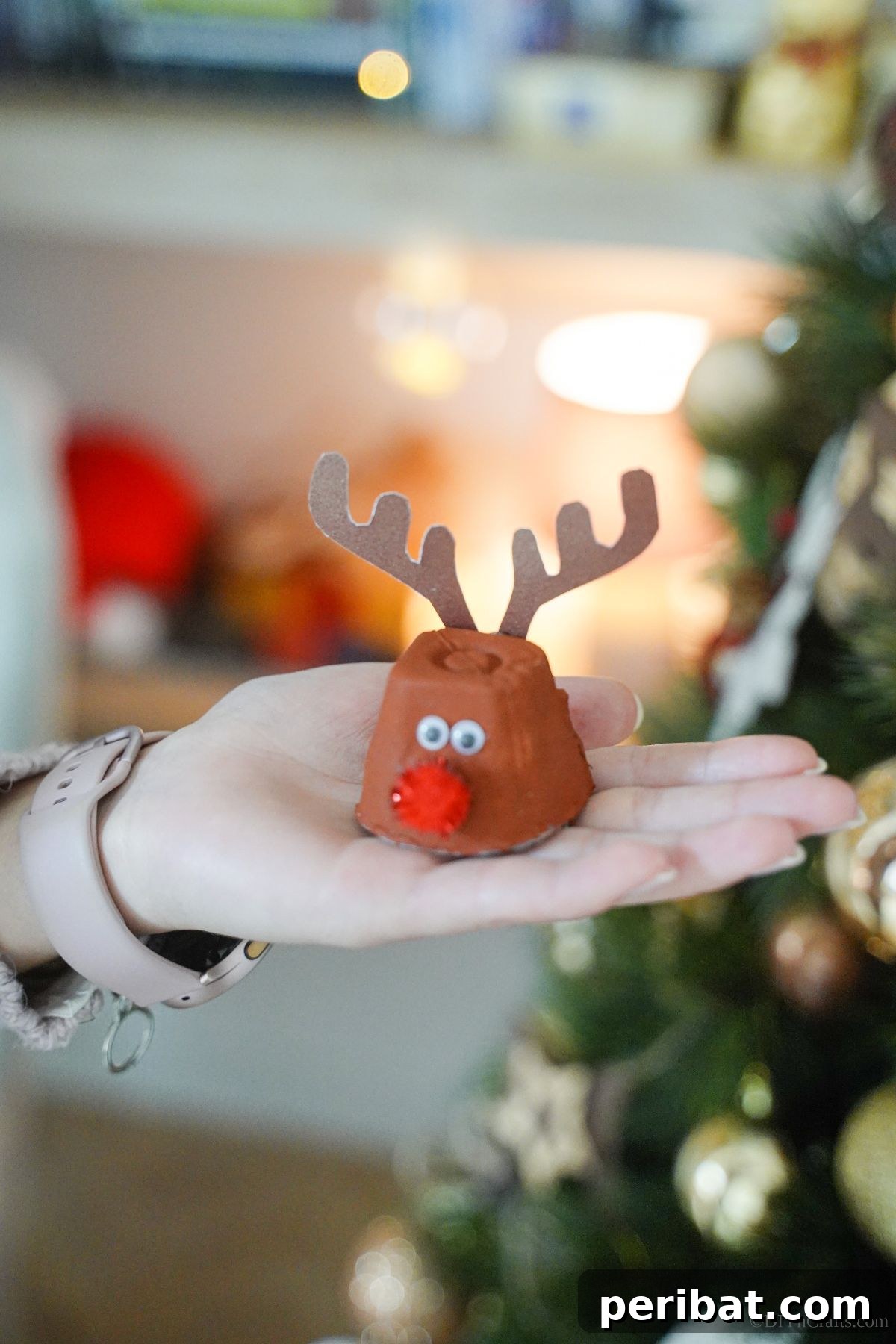 An egg carton reindeer thoughtfully placed in a lady's hand, showcasing the finished craft in detail.