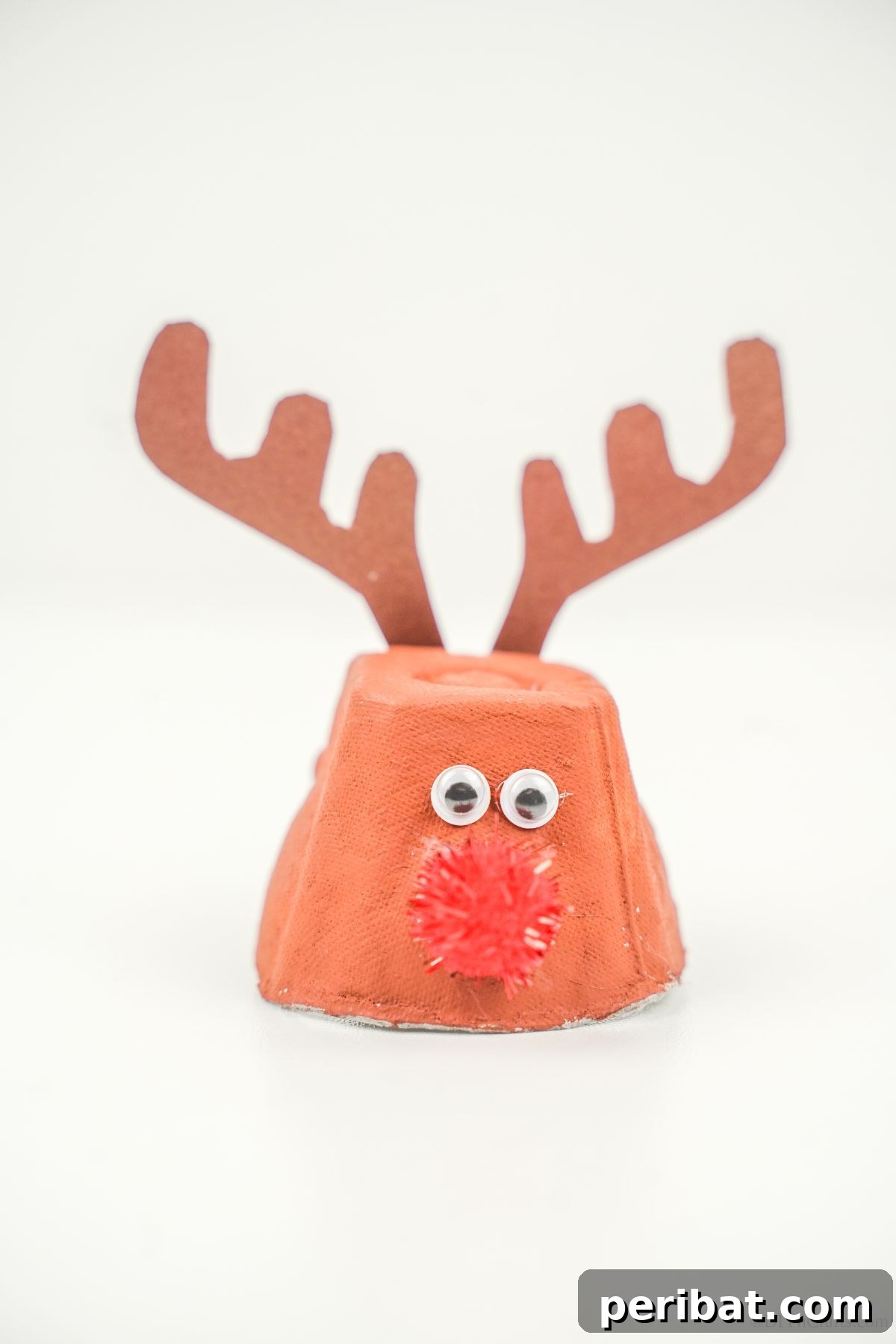 A whimsical egg carton reindeer craft sits on a pristine white table, ready to bring festive cheer to any space.
