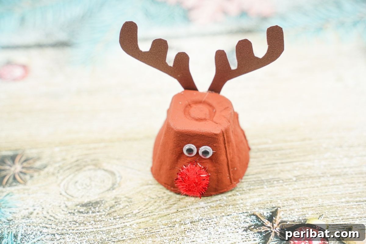 A finished egg carton reindeer craft placed on a wooden table, simple yet charming for a homemade Christmas decoration.