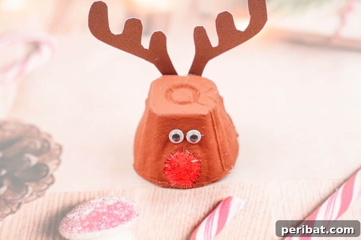 Festive holiday paper serving as a backdrop for a charming egg carton Rudolph reindeer, with candy canes subtly placed underneath.