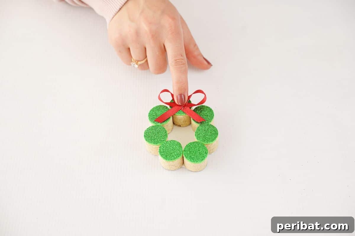 Repurposed Cork Wreath Charm 10 Hand holding a red bow, ready to be glued onto the top of a miniature cork wreath ornament