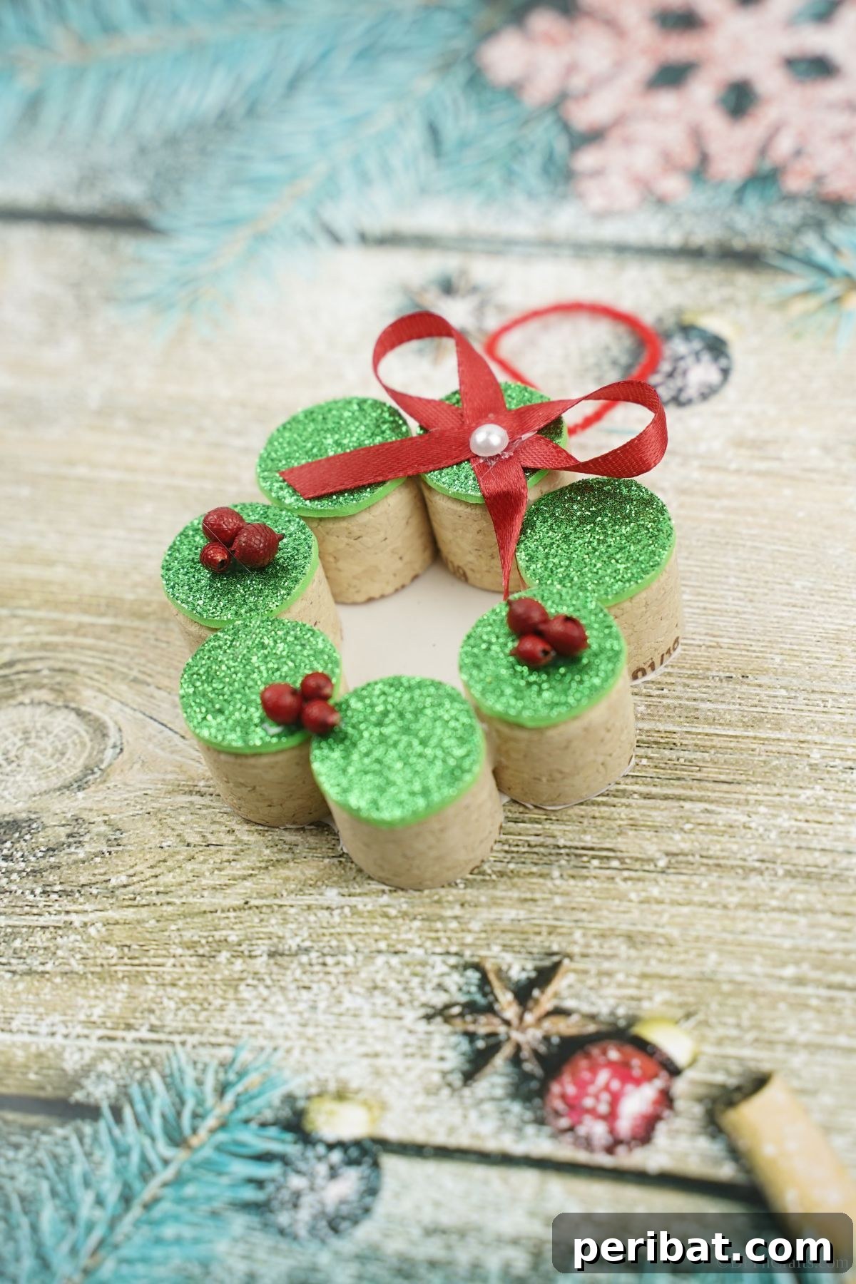 Repurposed Cork Wreath Charm 5 Miniature cork wreath with green top and red bow, on a table with a blue background