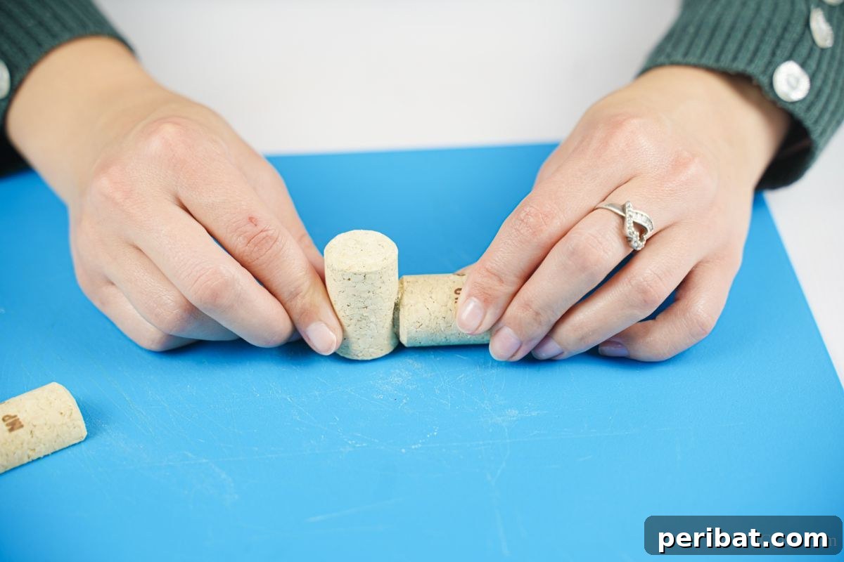 Wine Cork Express Christmas Ornament 11 Two wine corks being glued together on a blue crafting mat, one standing upright and the other lying horizontally to form the train's body