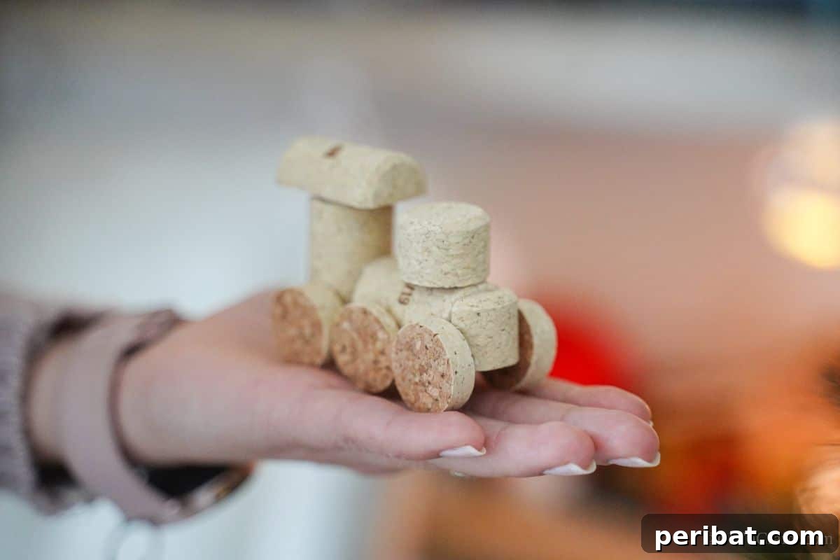 Wine Cork Express Christmas Ornament 5 A person holding a delicate wine cork train ornament in their hand, showcasing its handmade charm