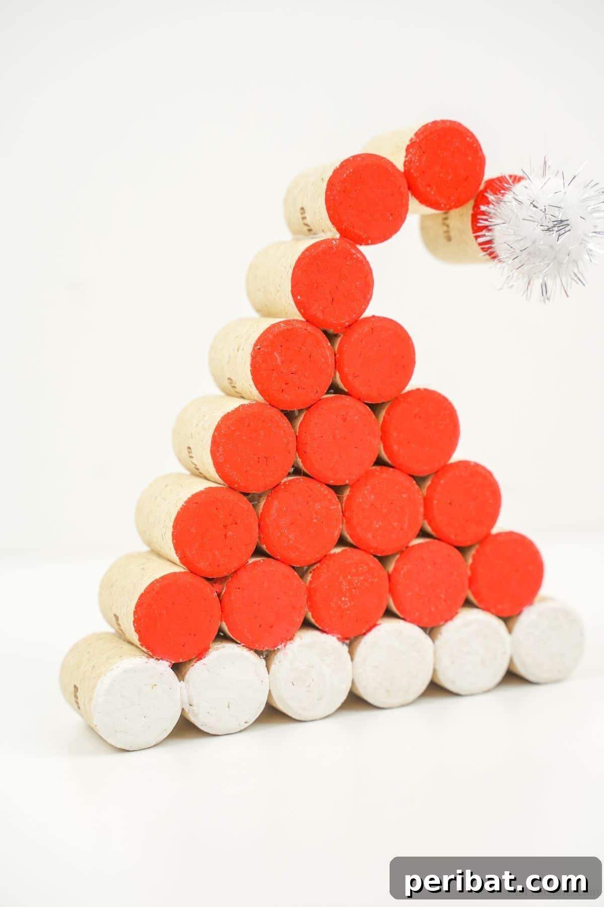 A completed wine cork Santa Claus hat, skillfully painted and adorned, rests on a clean white table, ready to bring holiday cheer.