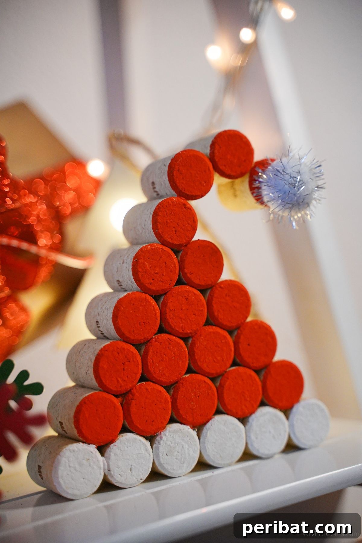 A hand-painted cork Santa hat decoration sits gracefully on the edge of a white mantelpiece, symbolizing festive charm.