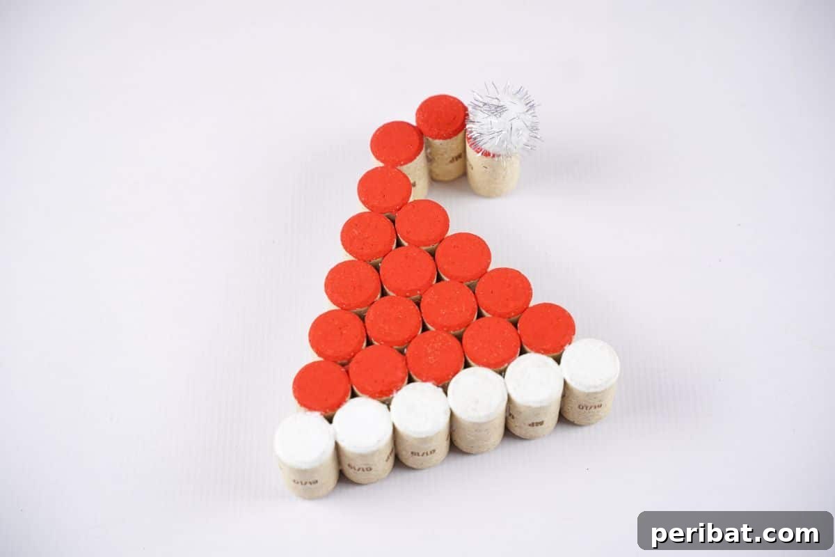 A beautifully painted wine cork Santa Claus hat sits on a pristine white table, ready for holiday display.