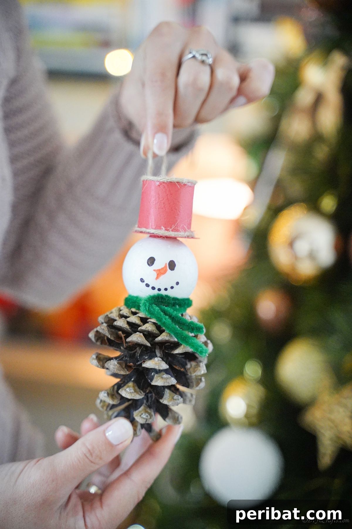 Woodland Pinecone Snowman Charm 15 snowman ornament being held in front of tree