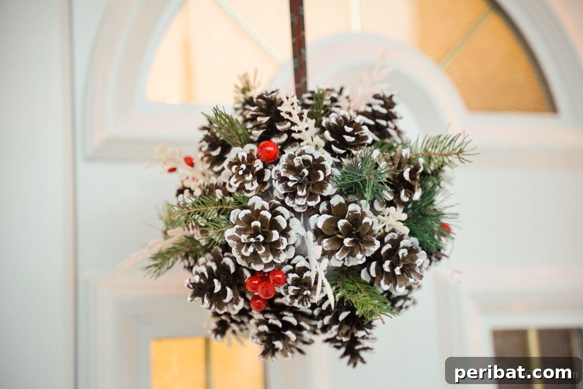 Festive Pinecone Ball Door Ornament 14 Christmas pinecone ball hanging against a white door with glass panes, showcasing the finished craft