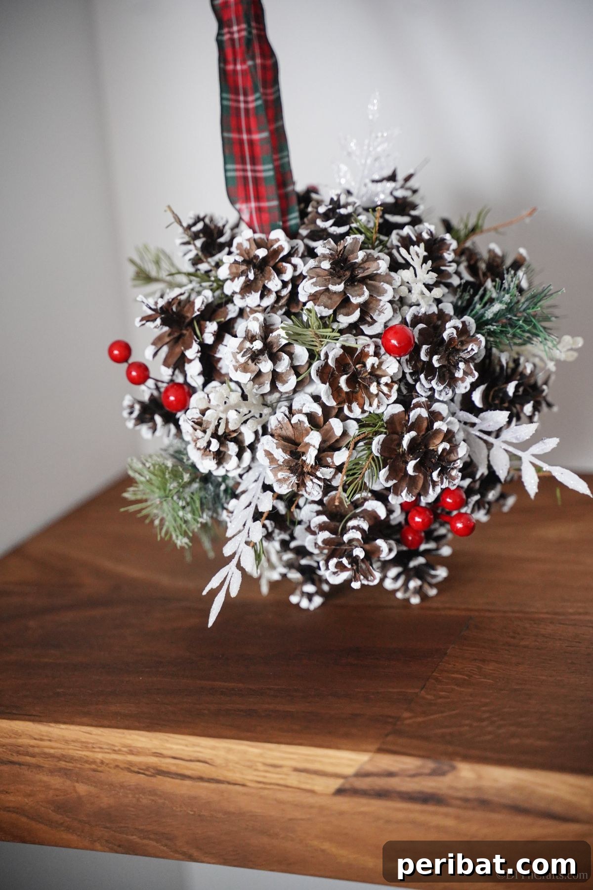 Festive Pinecone Ball Door Ornament 15 Christmas pinecone ball hanging against a white wall, showcasing its natural beauty and simple elegance