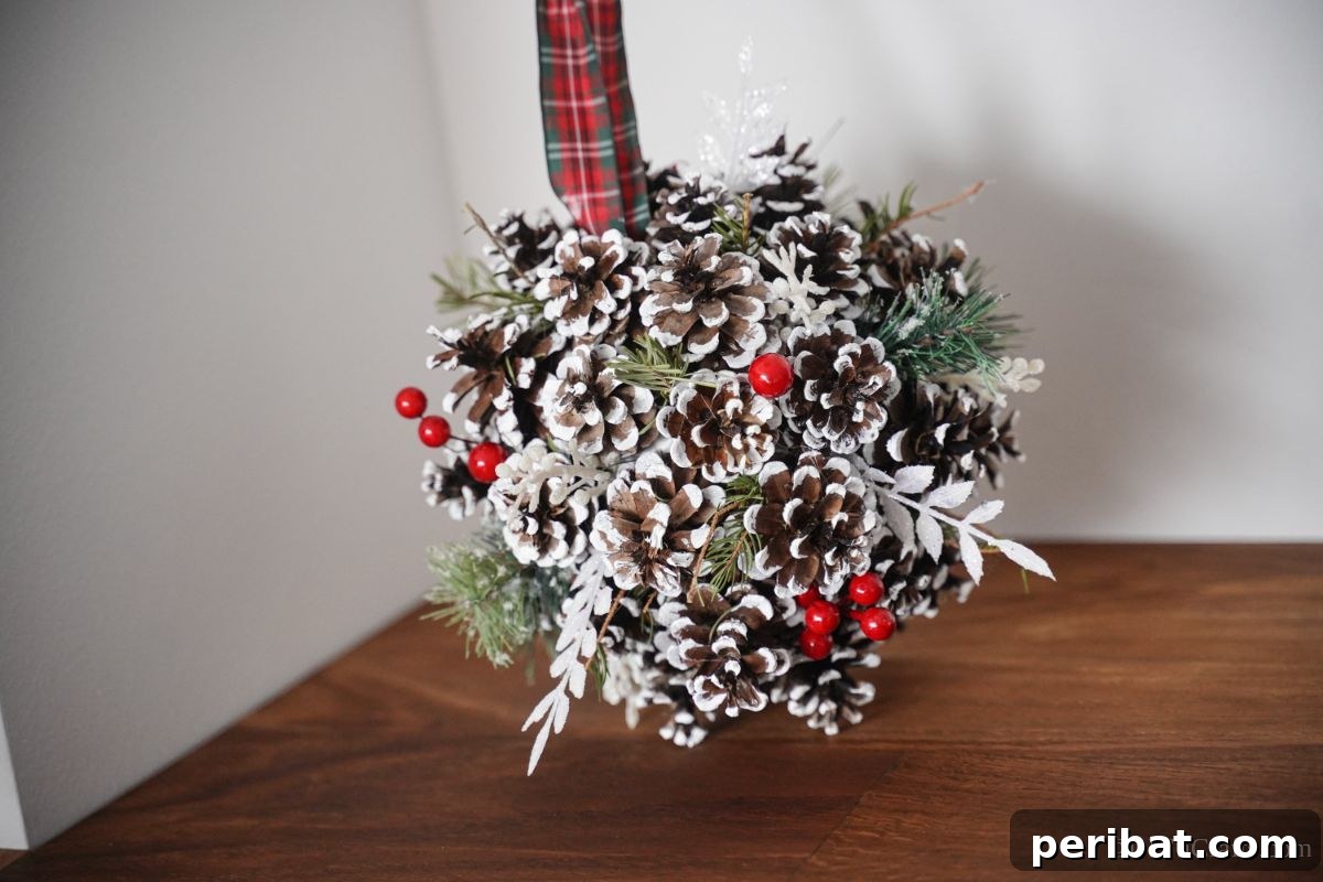 Festive Pinecone Ball Door Ornament 5 Pinecone door hanger against a white wall with a wood floor, highlighting its rustic aesthetic