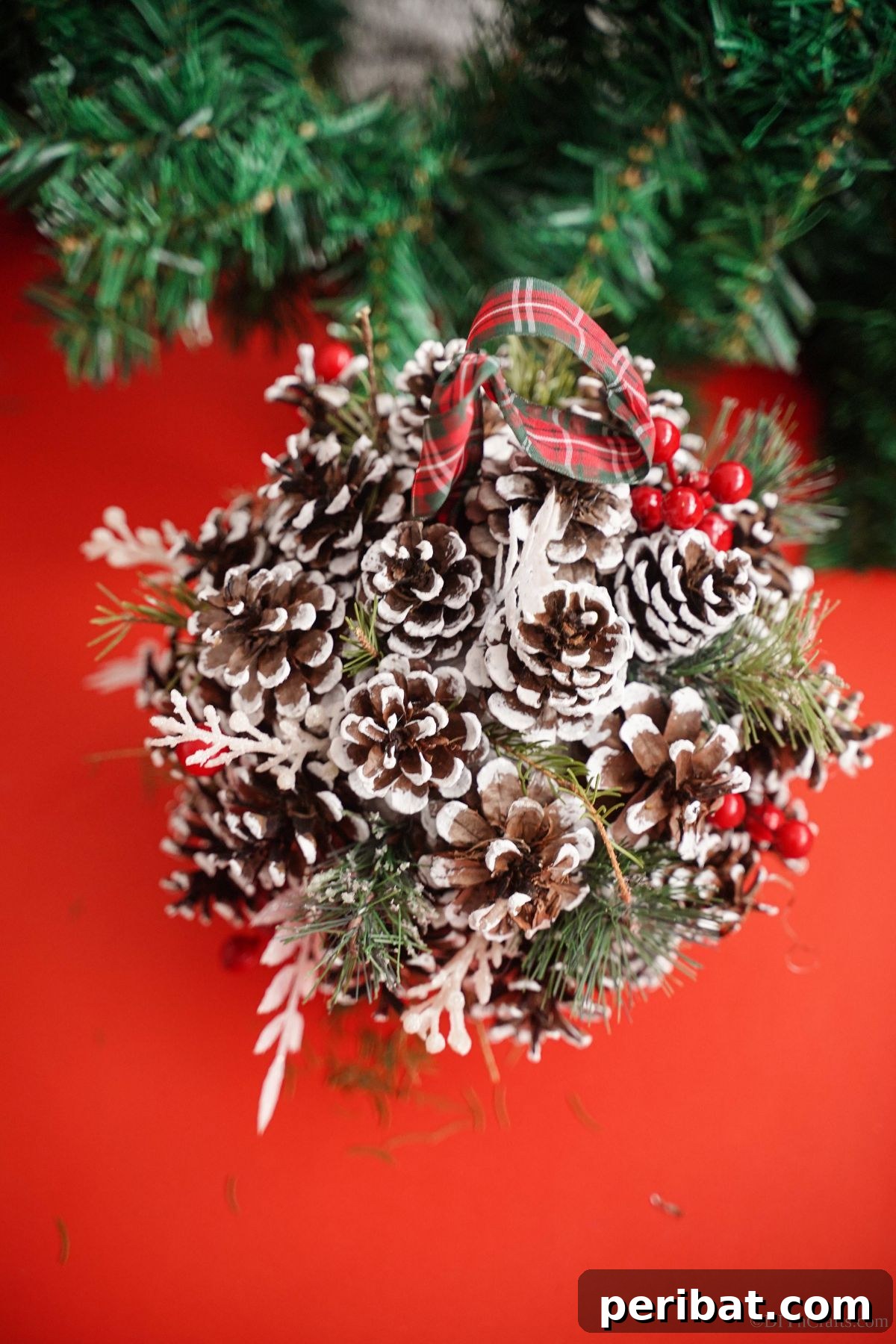 Festive Pinecone Ball Door Ornament 6 Pinecone ball door hanger resting on red paper, highlighting the festive color contrast