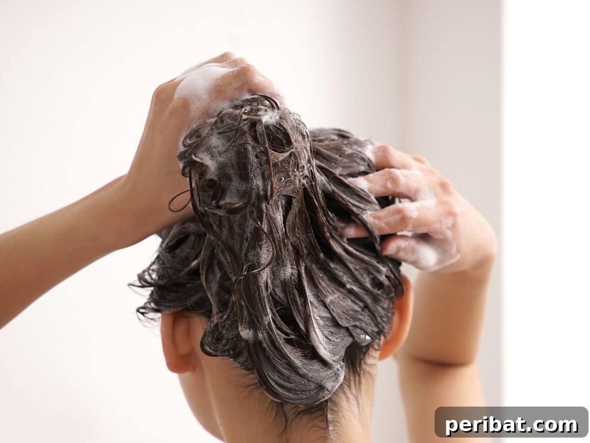A person gently washing their hair under a shower, using natural hair care products.