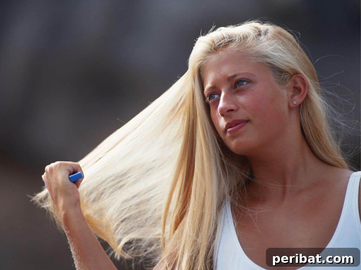 A young woman is gently combing her air-dried hair outdoors, avoiding heat styling tools.
