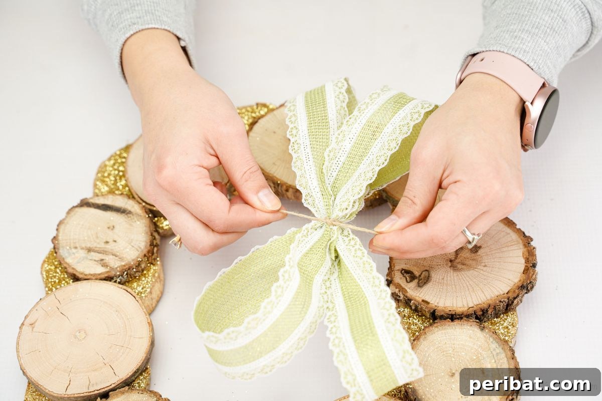 Natural Branch Slice Wreath Adorned with Pinecones 15 Tying string around a green and white ribbon bow