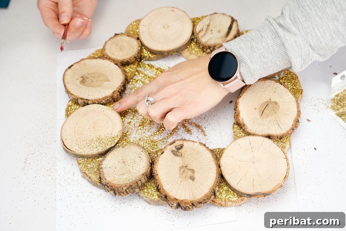 Natural Branch Slice Wreath Adorned with Pinecones 13 Gold glitter being brushed over wood slice wreath edges