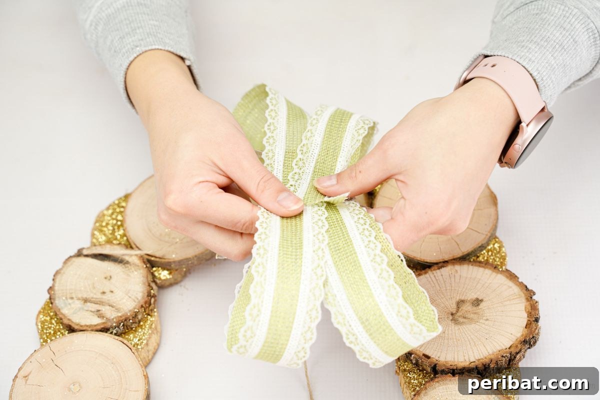 Natural Branch Slice Wreath Adorned with Pinecones 14 Hand holding green and lace ribbon loops above the wreath, forming a bow