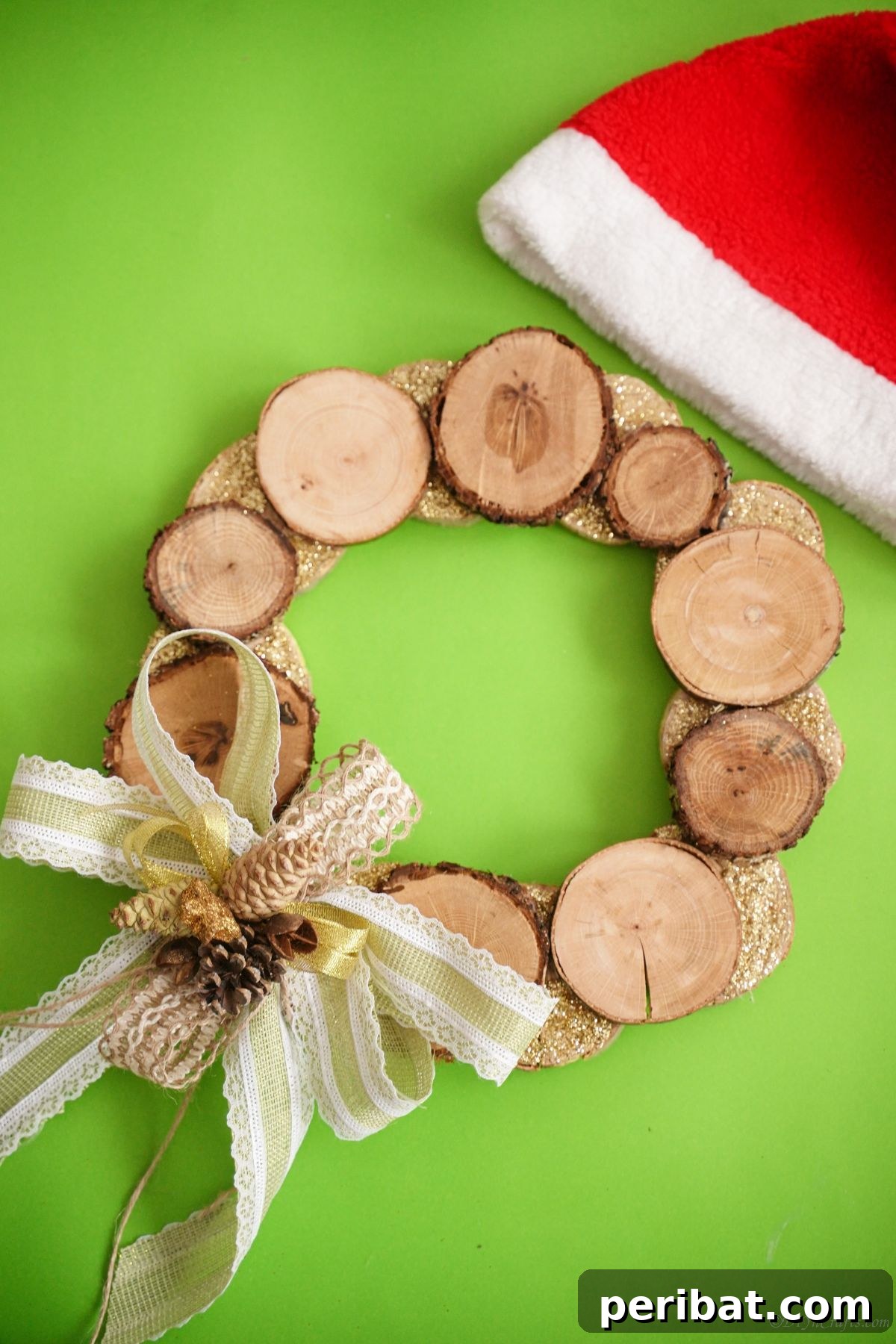 Natural Branch Slice Wreath Adorned with Pinecones 23 Bright green background behind a wood slice wreath with a Santa hat in the corner