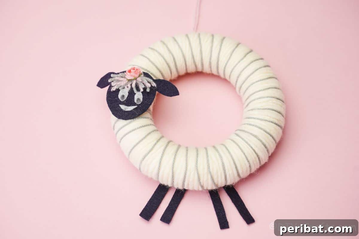 Whimsical Woolly Lamb Easter Wreath 5 Close-up of a fluffy white yarn sheep wreath with black felt details, presented on a vibrant pink background.