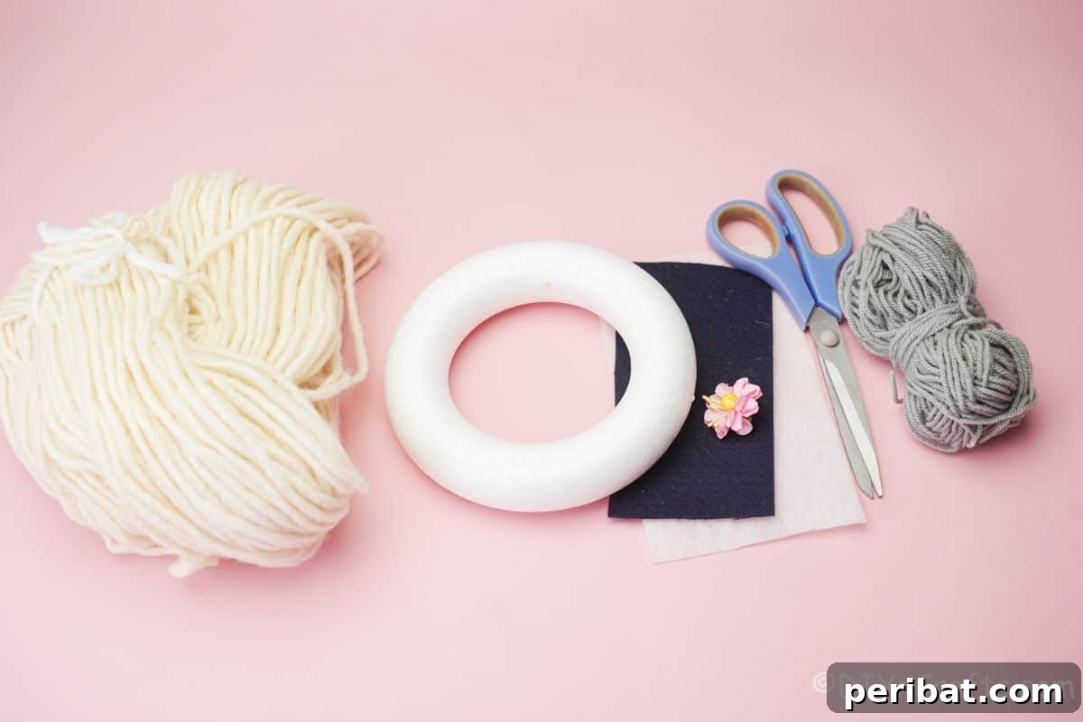 Whimsical Woolly Lamb Easter Wreath 7 Craft supplies neatly arranged on a pink surface: styrofoam wreath form, various yarns, felt sheets, scissors, and a glue gun ready for crafting.