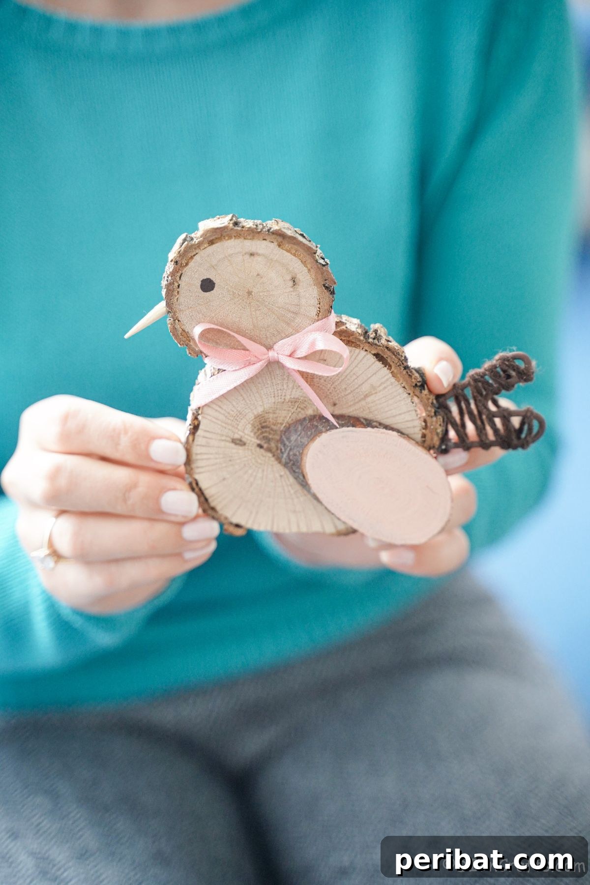 woman in teal sweater holding a cute wood slice chicken decoration