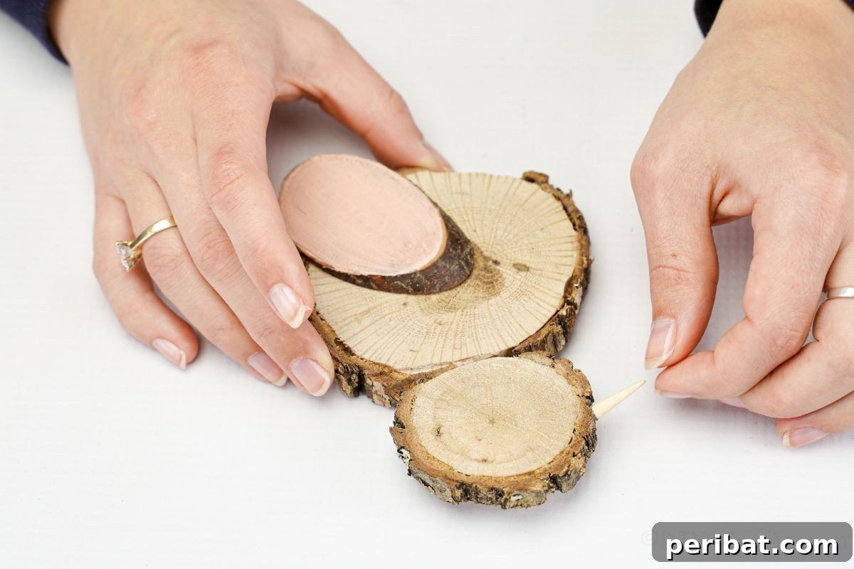 hand gluing a tiny wooden beak onto the wood slice chick