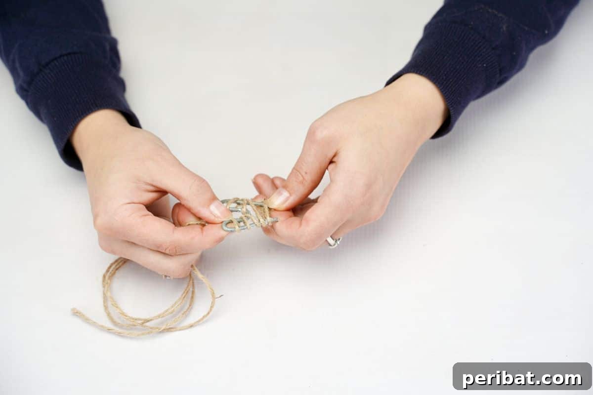 hand wrapping twine around a shaped metal wire to create the chicken's tail