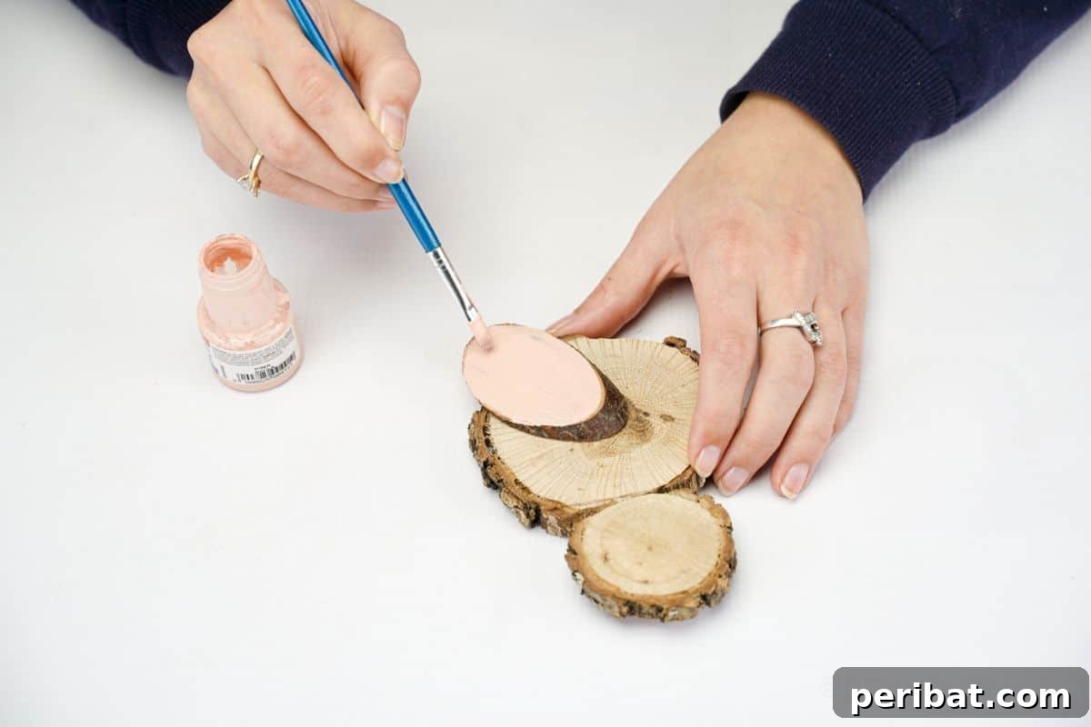 hand painting the wing on the wood slice chick with pink paint