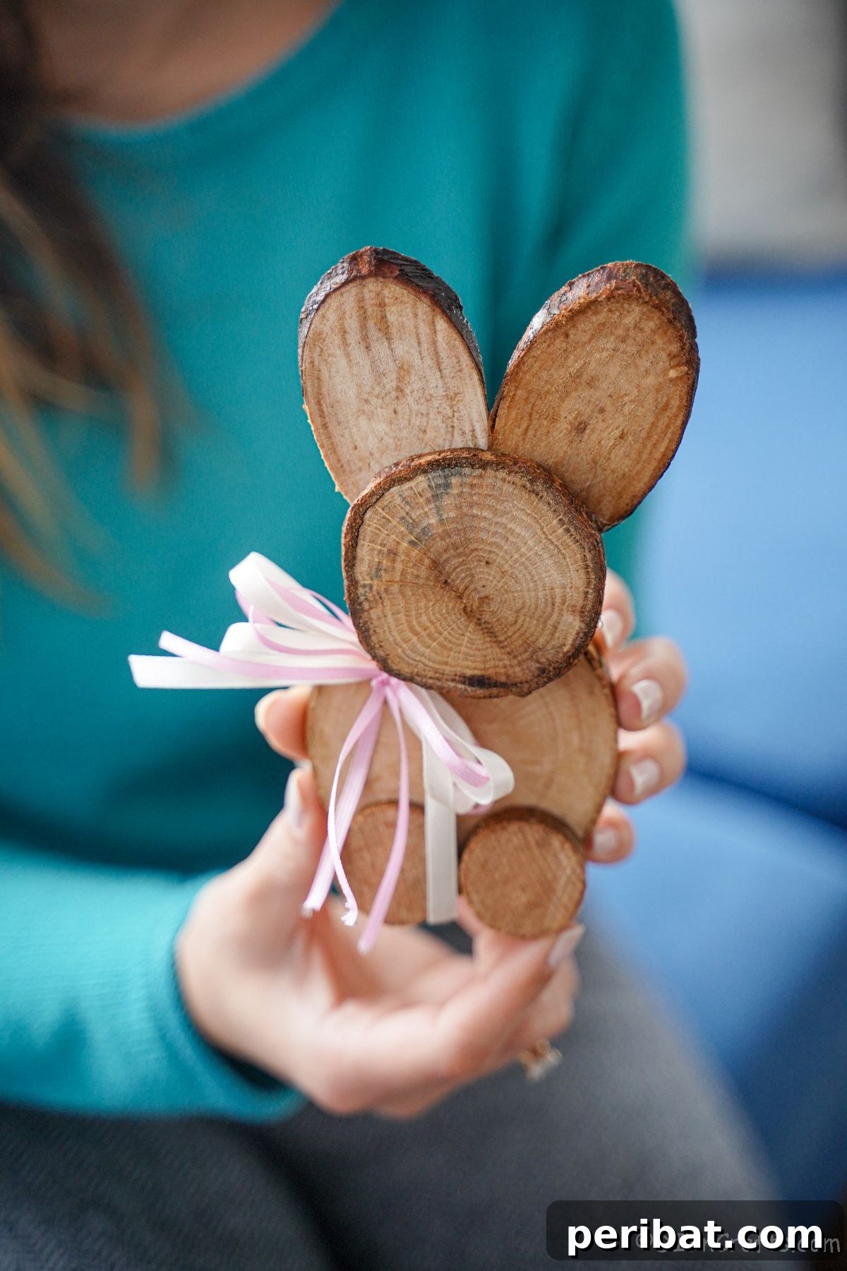 woman in teal holding wood slice bunny with pink ribbon on neck
