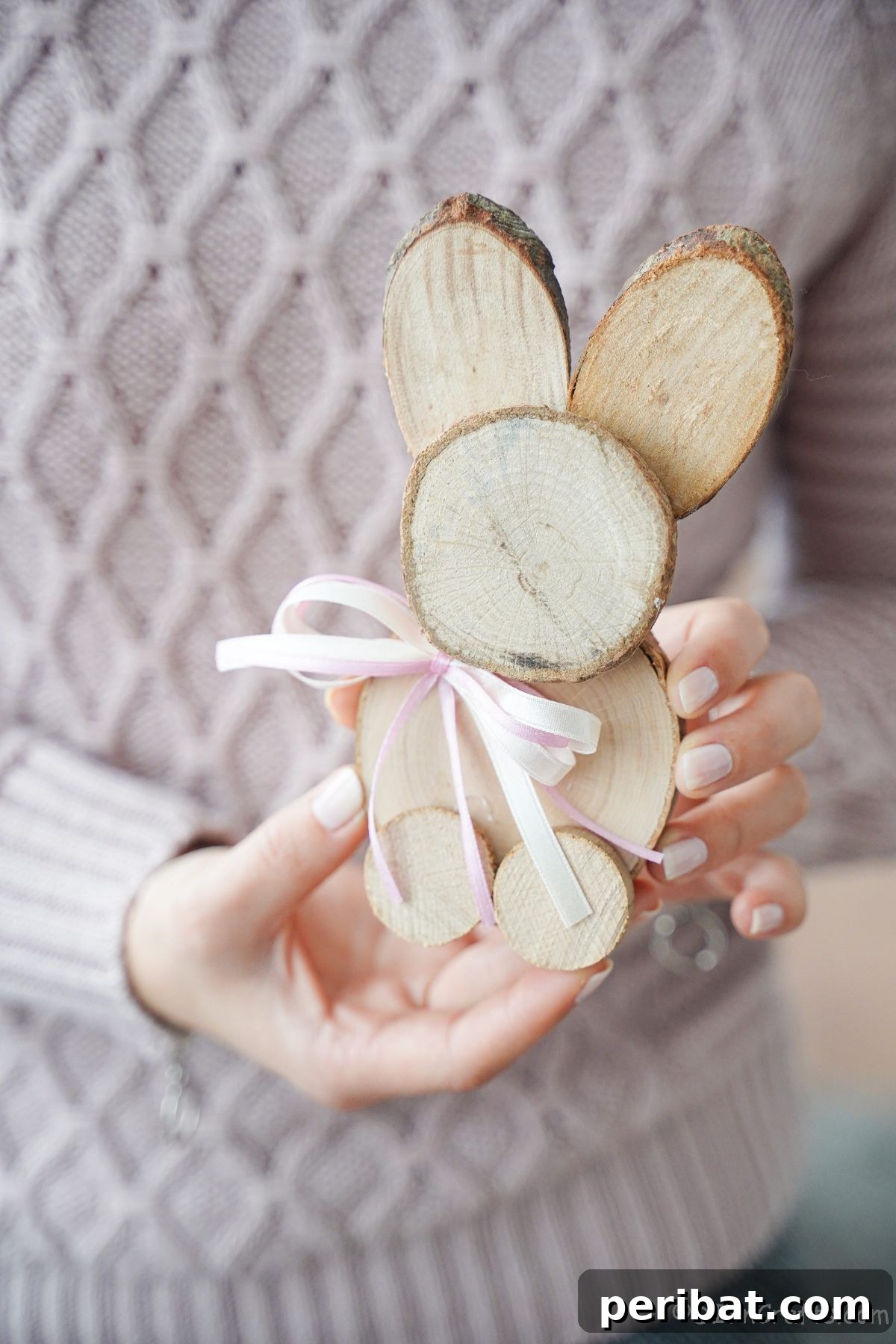woman in pink sweater holding wood slice bunny