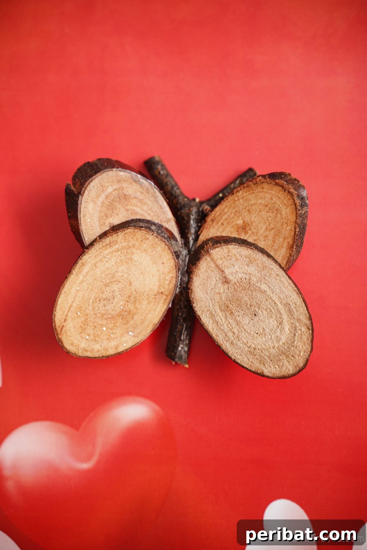 A completed wood slice butterfly resting on vibrant red paper, showcasing its rustic beauty and readiness for display