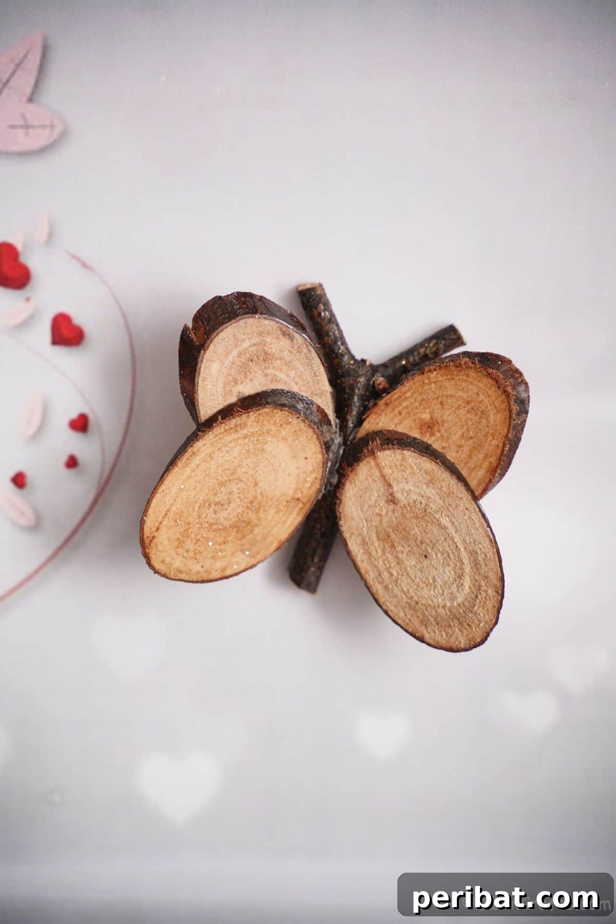 A charming wood slice butterfly positioned on a table next to a red and white plate, ready to adorn a cozy springtime setting
