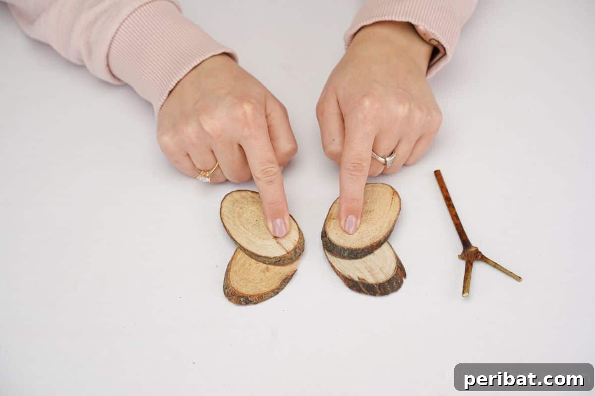 A hand carefully holding two wood slices together, demonstrating the gluing process for assembling butterfly wings
