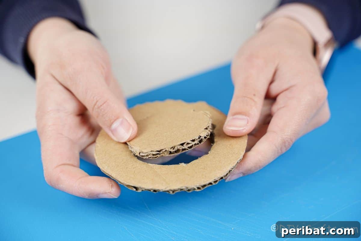 Hand gently pushing out the center of a cardboard circle, forming the wheel shape.
