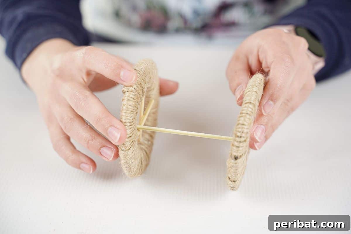Two twine-wrapped wheels being glued together with dowels, forming a cart base.